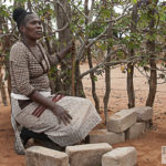 Sylvia Matoho mit Baobab-Setzling, hinter Stock